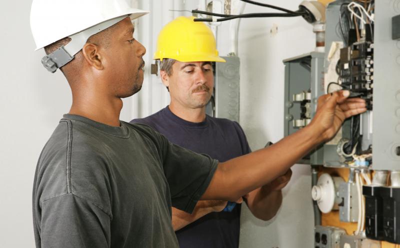 Stock photo: Electricians working on a panel.