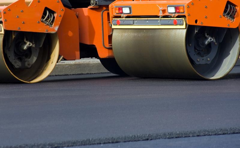 Road construction equipment rolls newly paved road