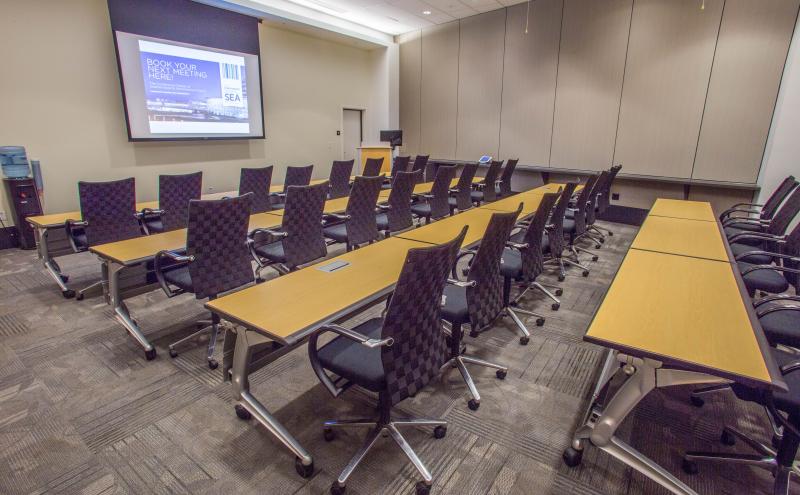 View from inside the Seoul Conference room showcasing a classroom style room set for 30 people, the podium, and dropdown projector screen