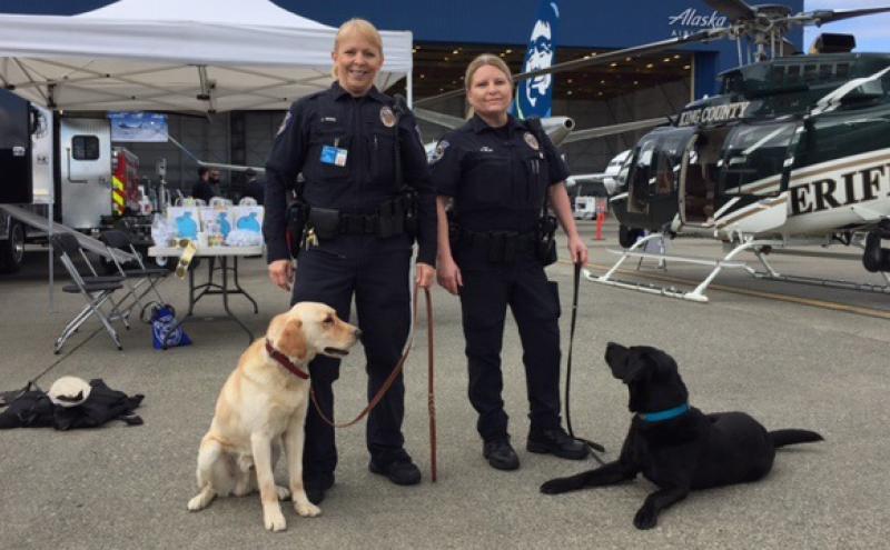 Two officers accompanied by a yellow lab and a black lab.