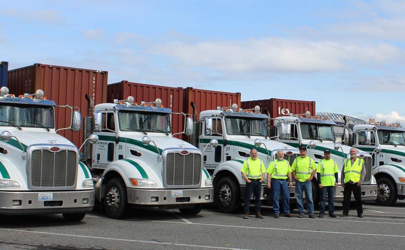 Employees of Castan, Inc. pose in front of trucks that operate at Ports of Tacoma and Seattle