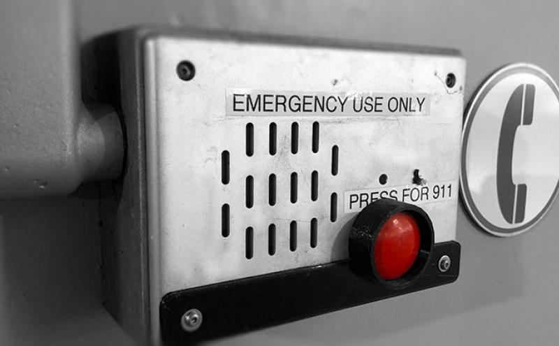 Airport emergency intercom with speaker, red 911 button, and signage.