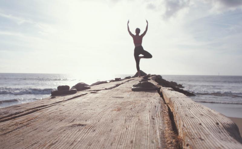 Woman doing yoga at the end of a pier.