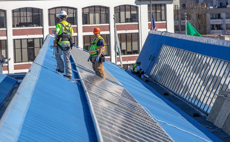 Workers installing solar panels on Pier 69 roof.