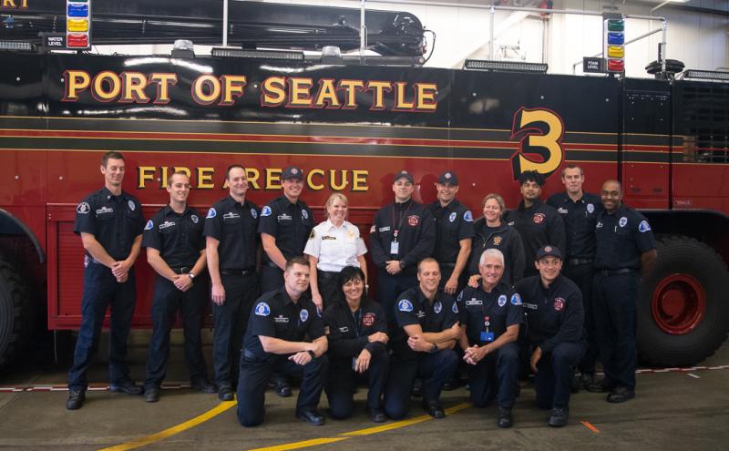 Stephanie McGinnis with her battalion in front of a red fire truck at the Port of Seattle fire department.
