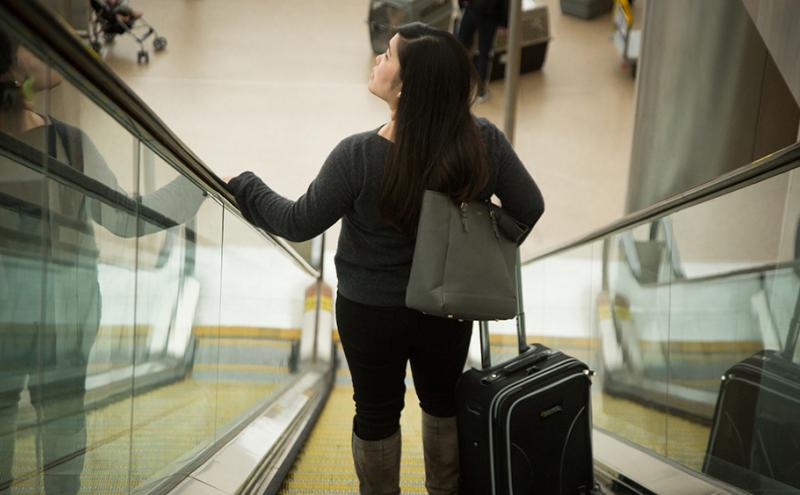 A woman going down the escalator at SEA Airport.