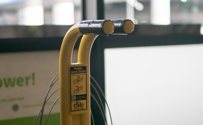 Public work stand with the instructions 'hang bike by seat or top tube'.