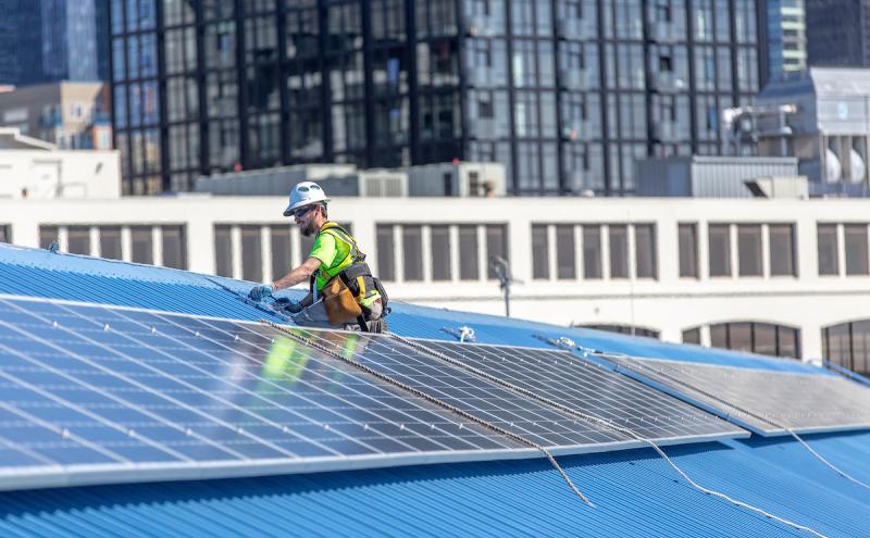 Worker installing solar panels on top of Pier 69 rooftop.