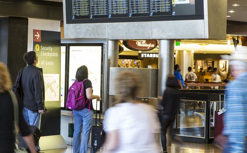 Passengers on the ticketing level of SEA Airport look at flight information, July 2016