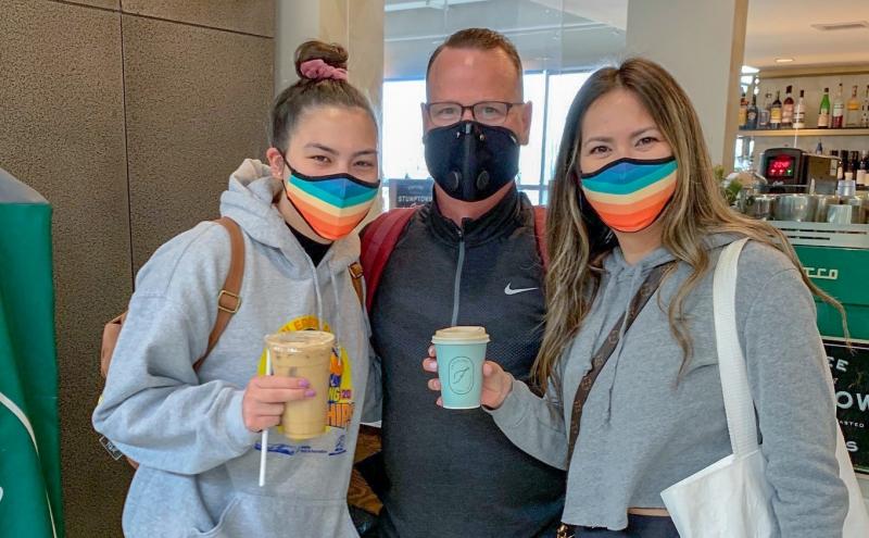 SEA Airport passengers wearing colorful face coverings holding coffee cups.