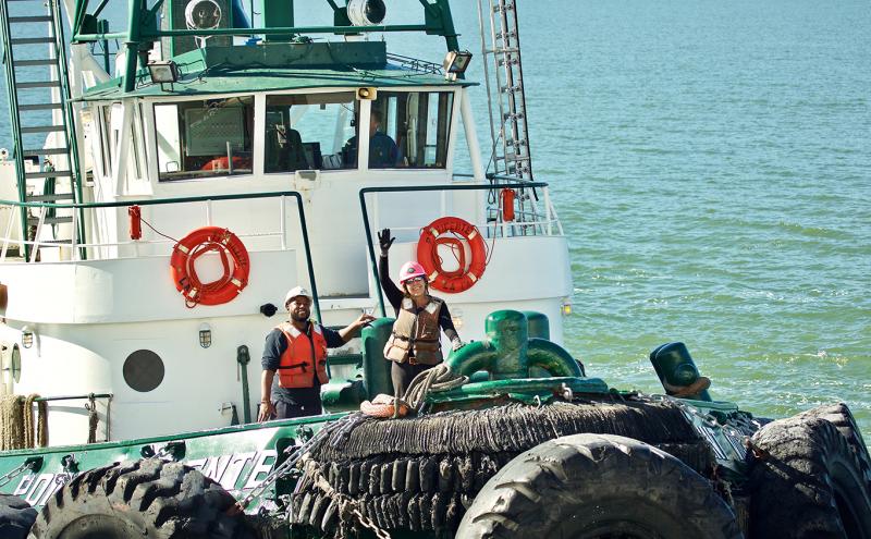 Fishermen wave from a boat.