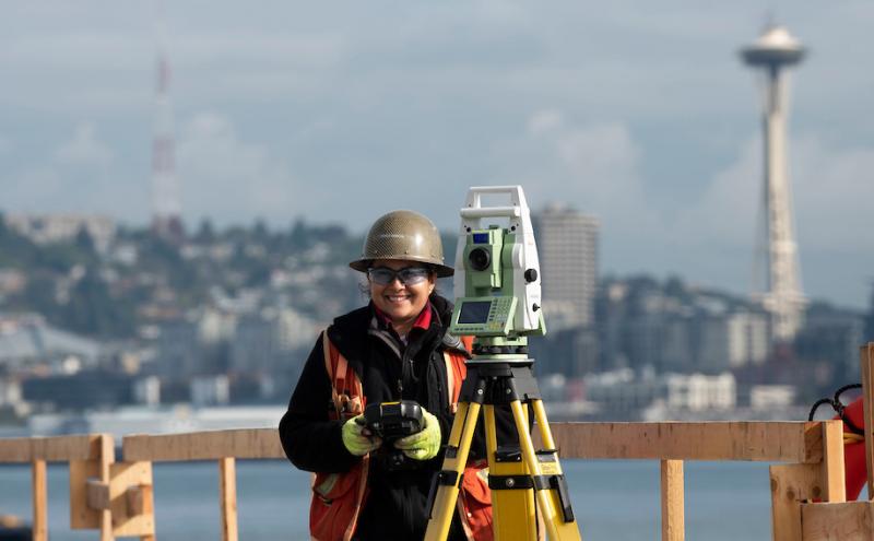Female construction worker using equipment on Seattle job site.