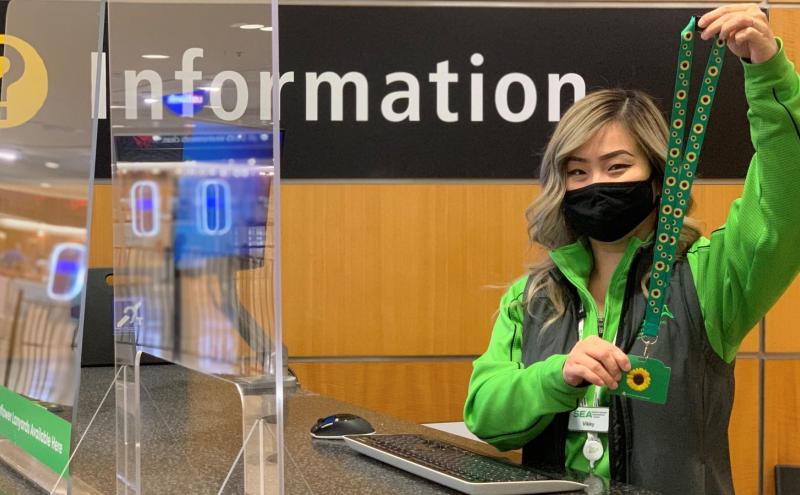 Pathfinder holds up a sunflower lanyard at the SEA information desk.