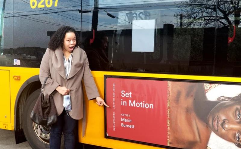 Marin Burnett standing in front of a bus with her artwork on it.