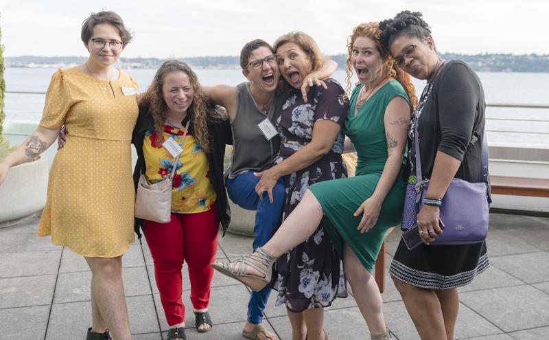 Diverse group of women share a laugh as they pose for the photo outside of the Port of Seattle waterfront offices.