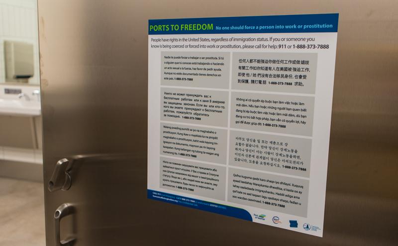 Human Trafficking Awareness sign on inside bathroom stall door at SEA Airport.