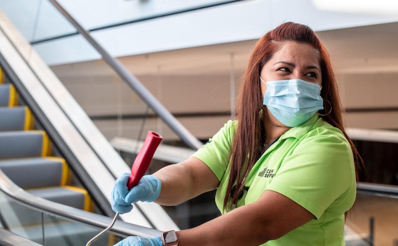 A Custodial Employee wearing a mask while cleaning