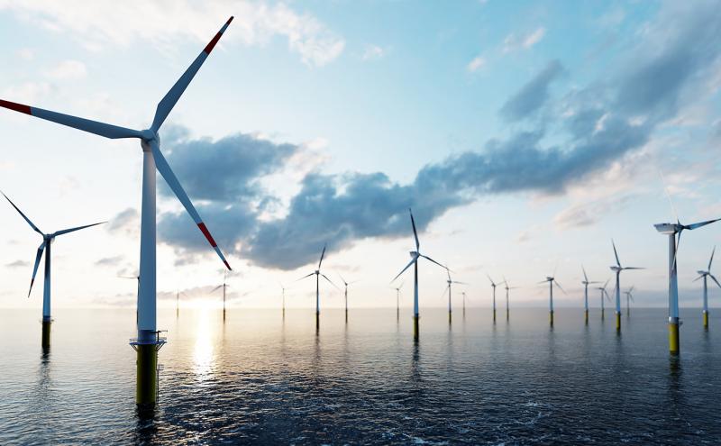 Offshore wind turbines against a sunset sky.