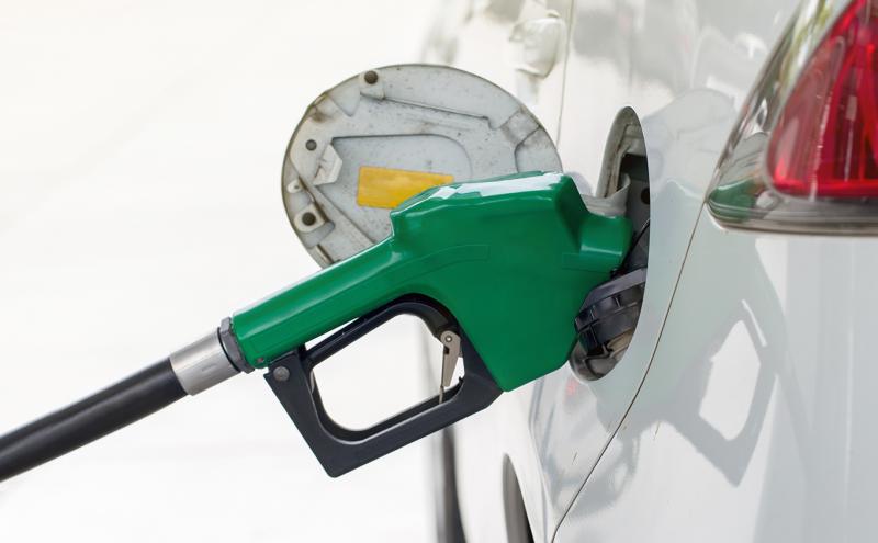 Green fuel pump in a white car with red taillight, stock image.