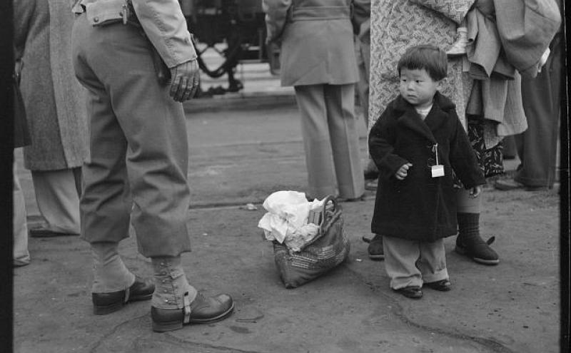Japanese child standing next to a soldier.