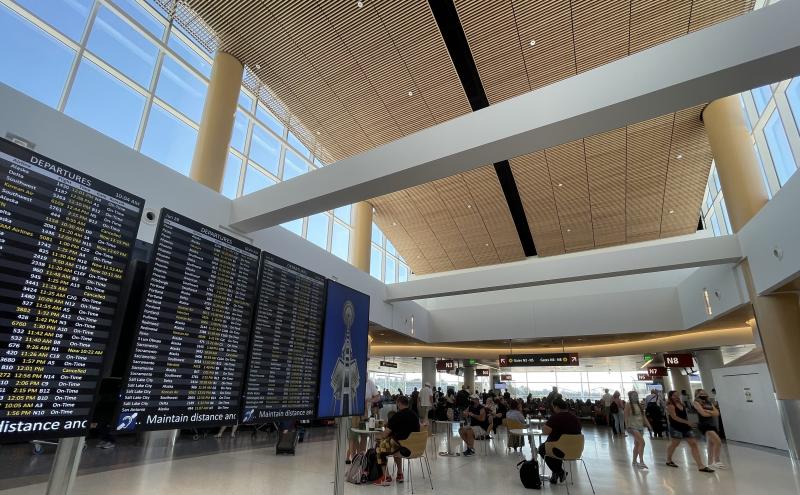 Airport concourse with departure boards and travelers.