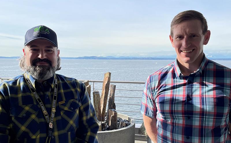 Chad Aldridge and Commissioner Ryan Calkins on the deck of Pier 69 with Elliott Bay in the background.