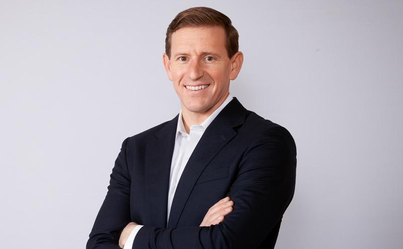 Commissioner Calkins in a dark suit jacket and white shirt against a white background.
