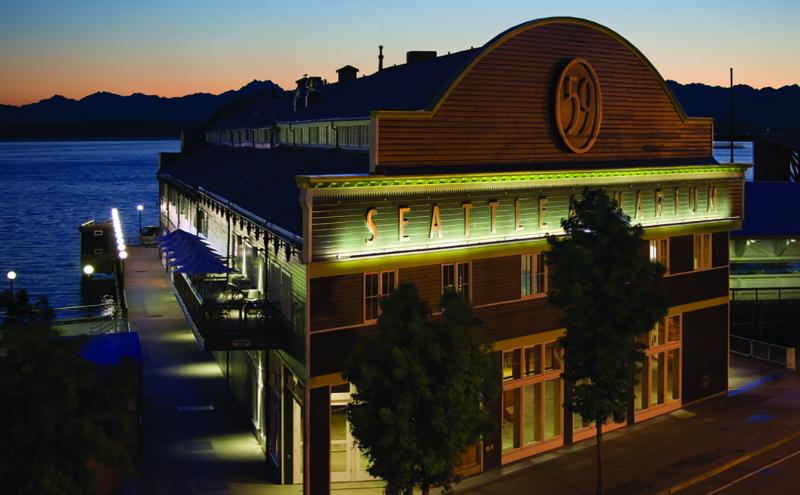 Dusk Seattle Aquarium facility at Pier 59 with orange and pink sky and blue water of Elliott Bay