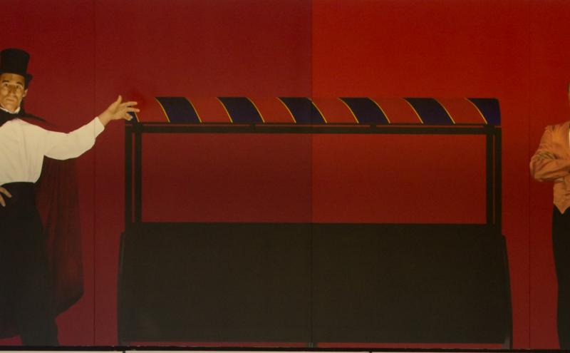 Painted panel showing a magician in a top hat gesturing toward an empty open box, with a second figure standing to the right. 