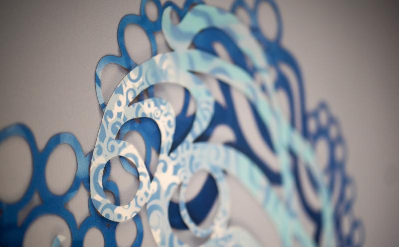 A close-up detail of the vinyl installation showing layered blue rings and curling white scroll patterns.
