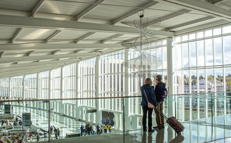 Two people with luggage stand overlooking the Grand Hall at the IAF 