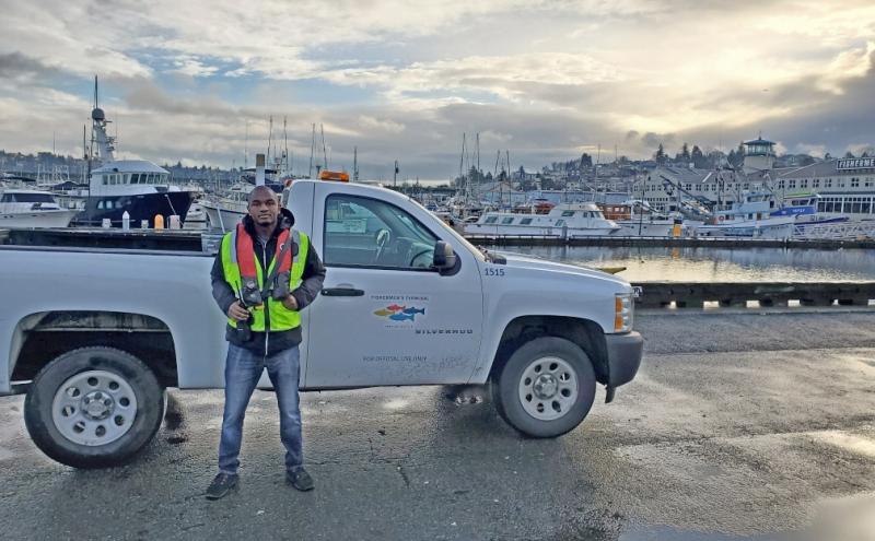 Souleymane wearing a PFD and standing in front of a Fishermen's Terminal truck