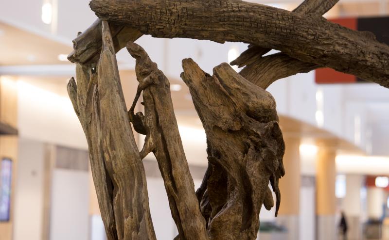 A close-up detail of the legs and torso showing texture and grain of the bronze structure. 