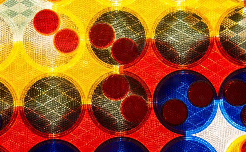 Close-up of circular reflectors in two sizes, smaller ones layered on top of larger ones, each with a faceted surface.