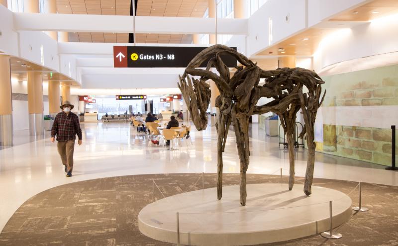 A cast bronze horse sculpture constructed from interlocking branches displayed on a circular platform. 