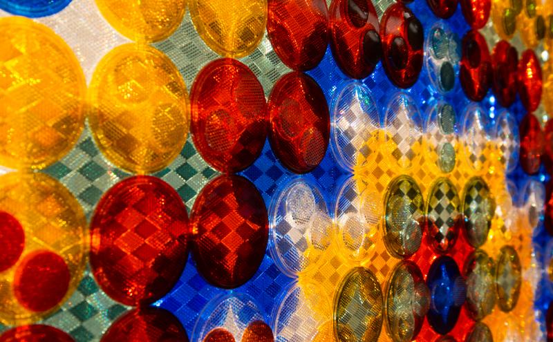 Close-up of circular reflectors mounted in front of a separate backing layer, which has it's own raised geometric pattern visible in the gaps between the circles. 