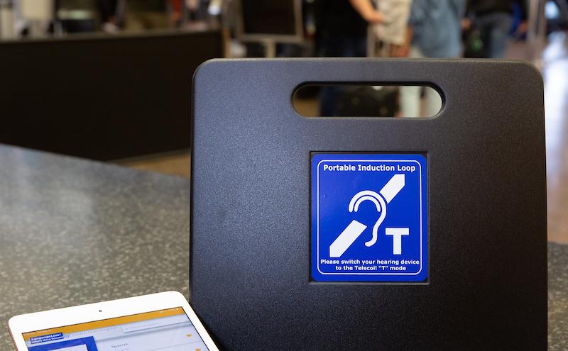 Portable induction loop device and tablet displayed on a counter in an airport.