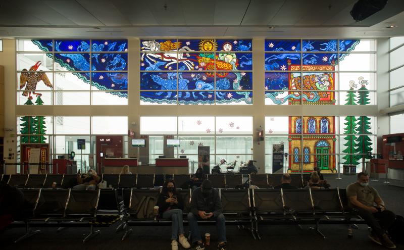 The full stained glass installation spanning the gate wall, with stained glass panels of trees and a building extending down both sides. 