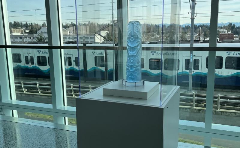 Full view of the crystal totem-form sculpture on a pedestal, displayed in a glass case. 