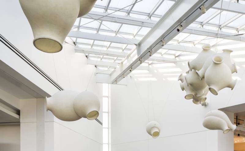 In this wedge-shaped section of A Concourse, artist Peter Shelton has created an environment of many complimentary forms: light and heavy, translucent and opaque, floating and earthbound. Fiberglass “clouds” are suspended from the skylights, while identically shaped cost iron “clunkers” occupy the steps. 