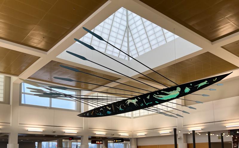 Full view of An aluminum and dichroic glass boat flies with thirty suspended, wing-like oars