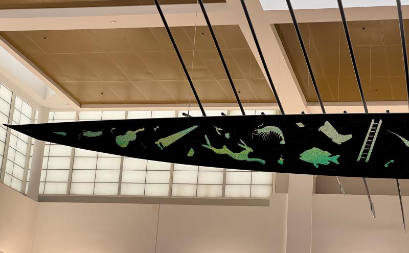 Front half of boat with cut-outs in the sides of the boat reveal images of tools, plants, and animals.
