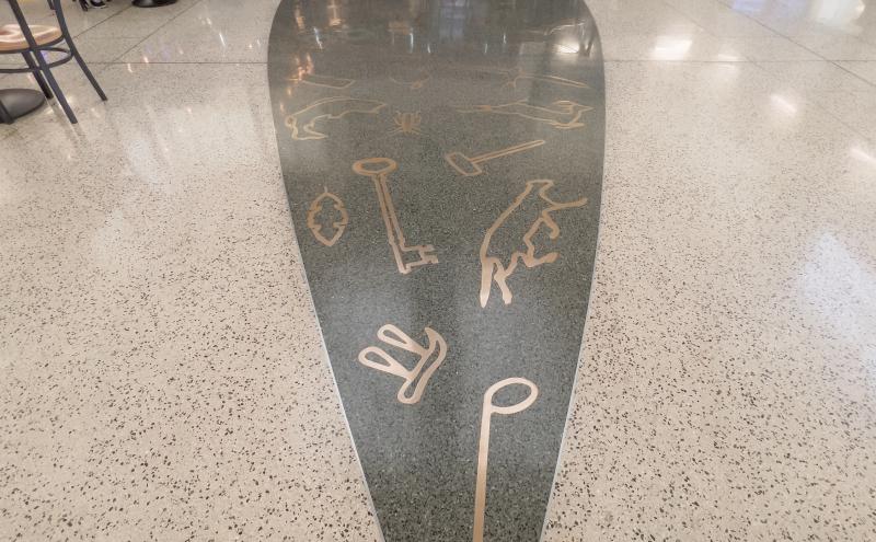 The terrazzo floor representing the lands and the seas and outline of boat on floor like a shadow, it is the color gray.