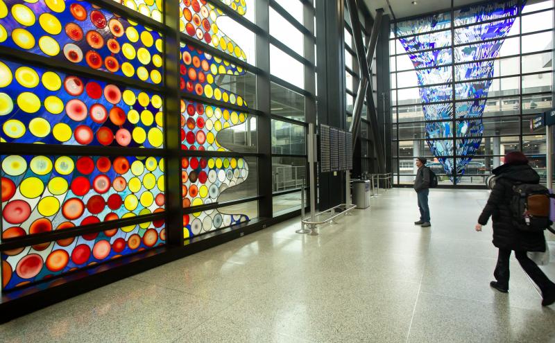 Cow on its Side by Dick Weiss:  A stained-glass window mosaic of circular rondelles set against wavy lines with a rippling, humped silhouette along the right edge. 