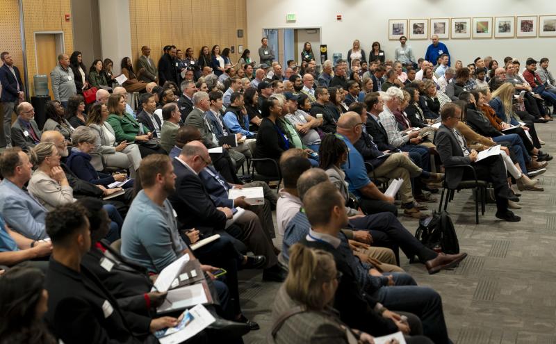 A large audience seated in a conference room during a presentation.
