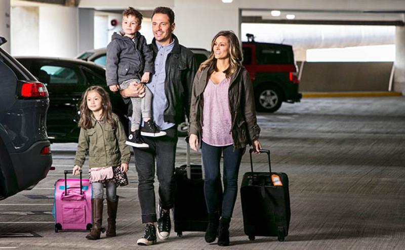 A family walks through the SEA parking garage with luggage.
