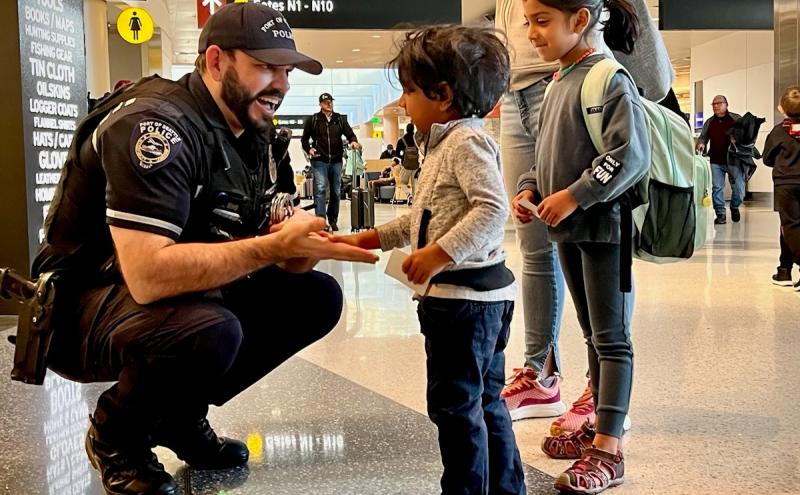 Police officer greeting two young children at the airport.