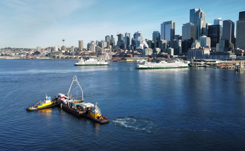 Seattle waterfront with ferries on the water and small work vessels in the foreground.