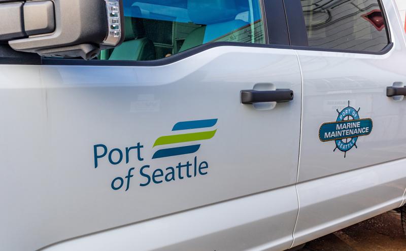 Side view of a white truck displaying the Port of Seattle logo and a Marine Maintenance emblem on the doors.