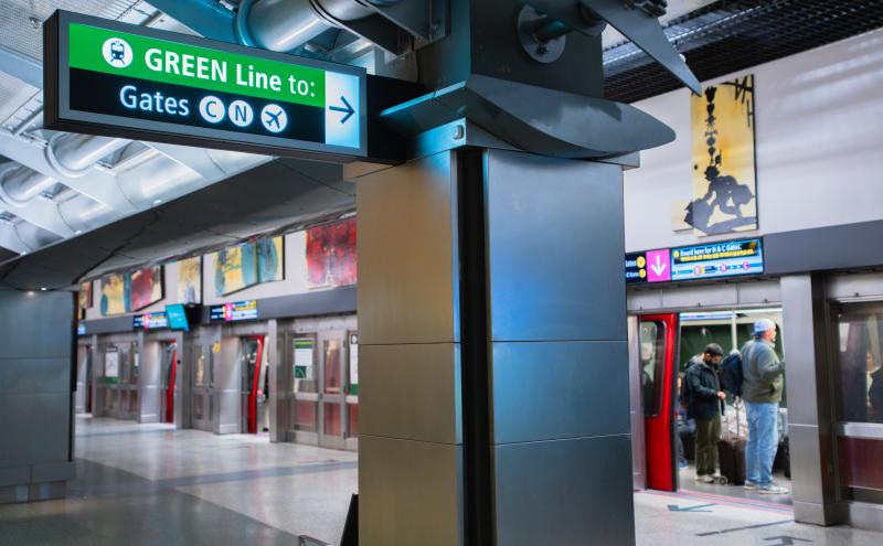 Overhead airport sign with a green header reading ‘GREEN Line to:’ and directional symbols pointing right toward Gates C, N, and X.
